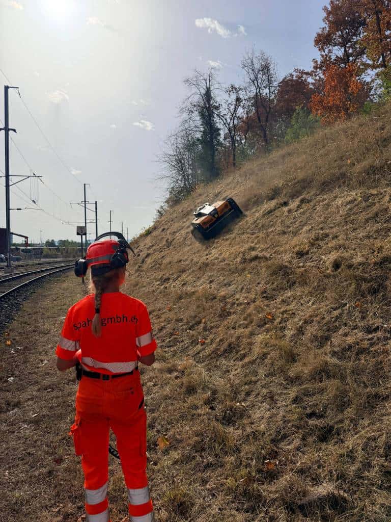 Bedienperson in Warnkleidung beobachtet den AS 990 Tahr RC an einer steilen Bahnböschung